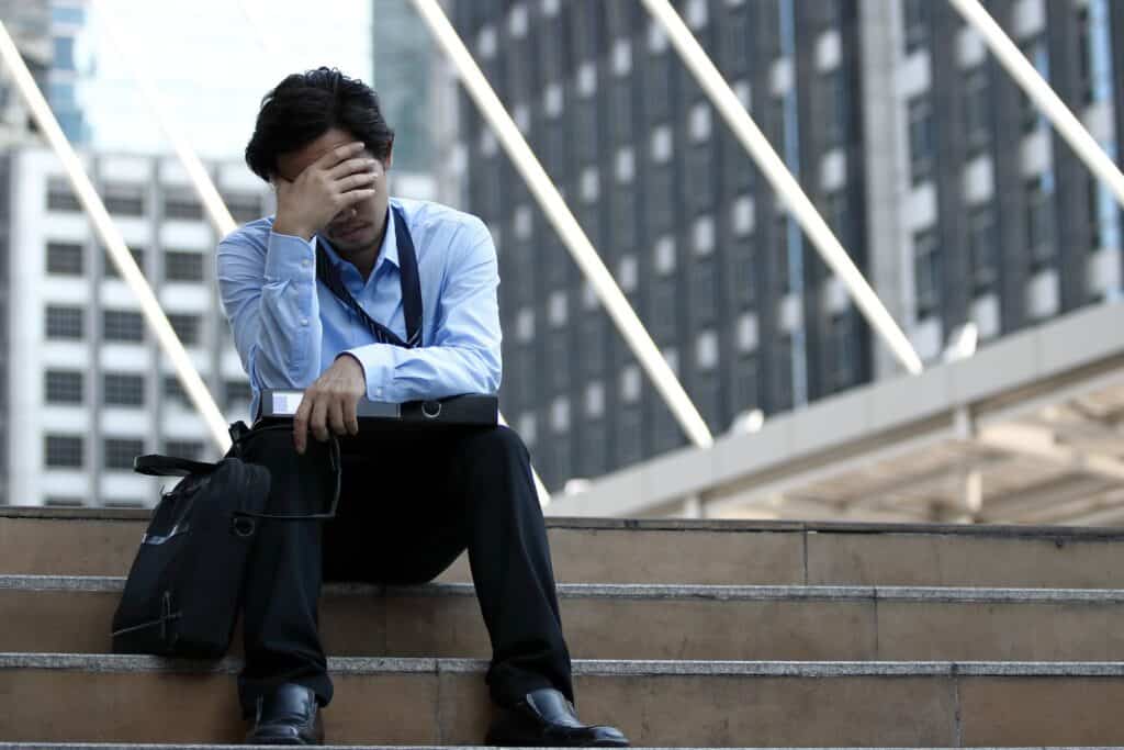 Stressed businessman sitting with his head in his hand
