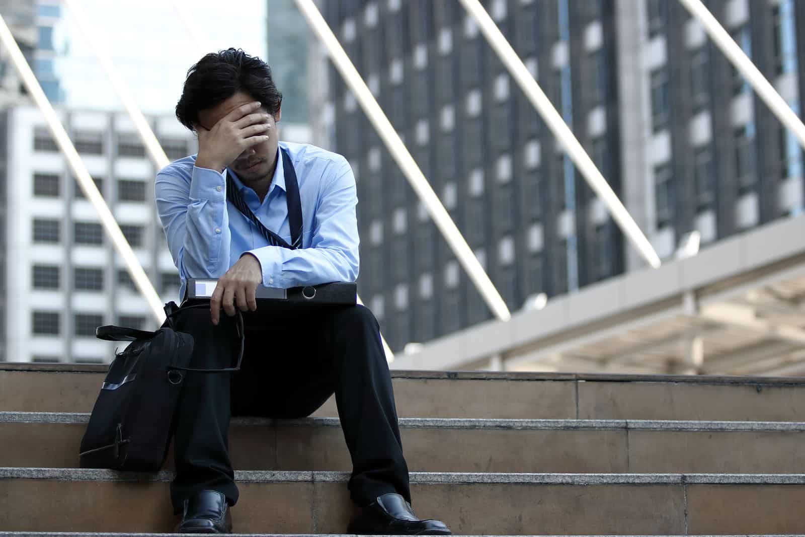 Stressed businessman sitting with his head in his hand