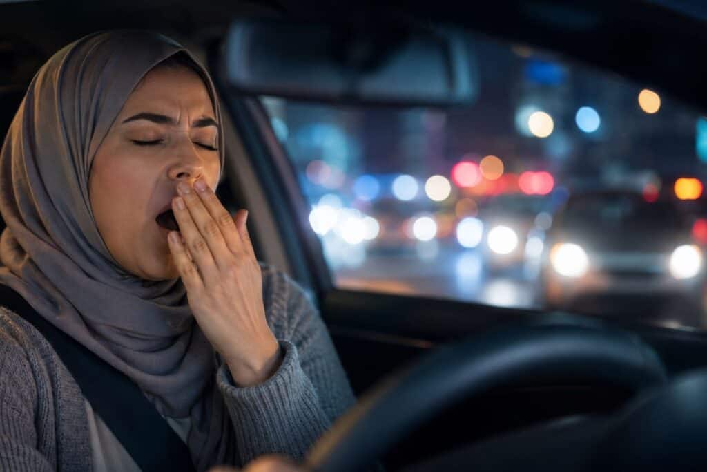 Woman yawning while driving at night