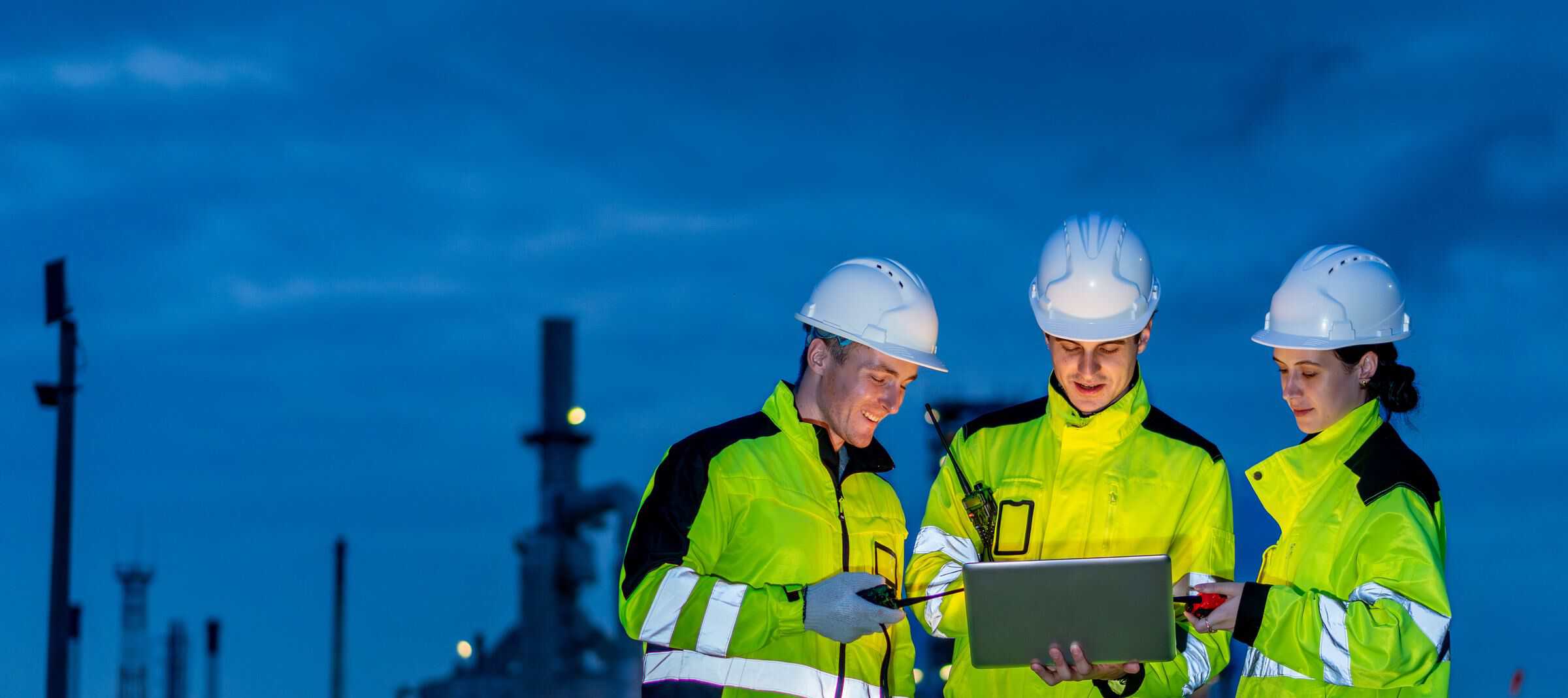 Night-shift team in high-vis reviewing work on a laptop