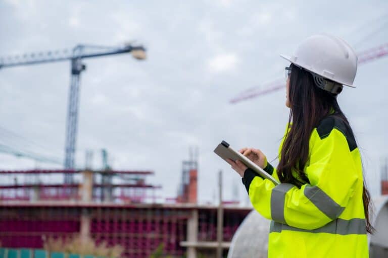 Construction worker in high-vis on site with cranes