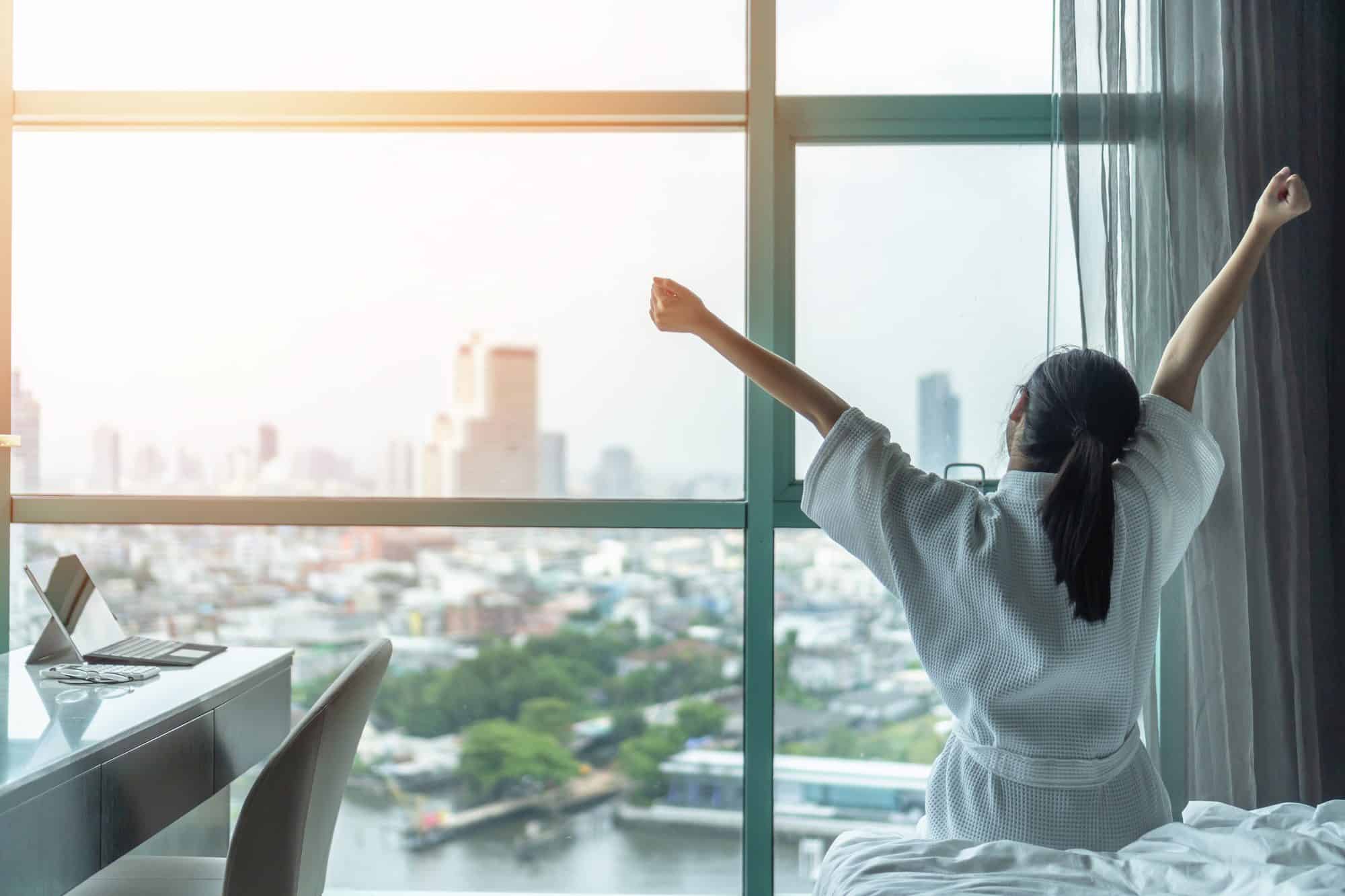 Woman stretching by a window after waking refreshed
